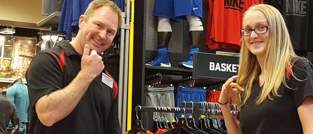 Two Scheels employees smile for the camera in the store.